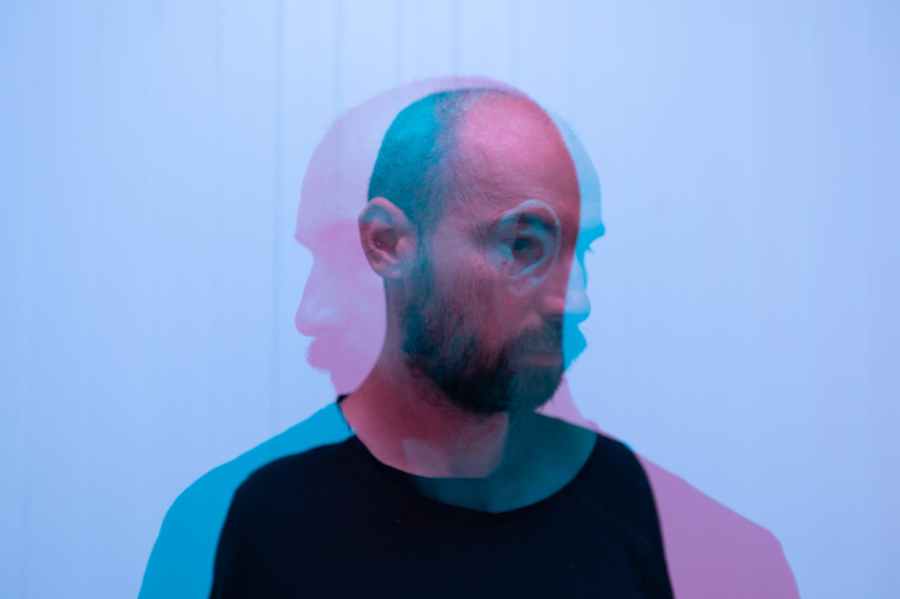Double exposure of a man. One exposure faces left in pink, the second faces right in blue.