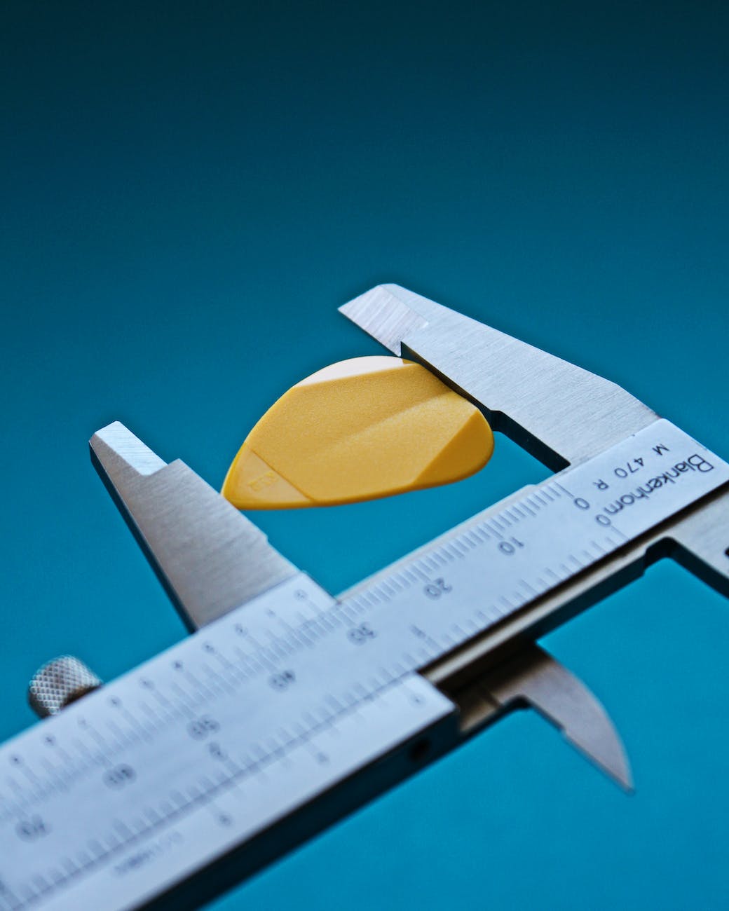A micrometer measuring a yellow chip in the shape of a heart