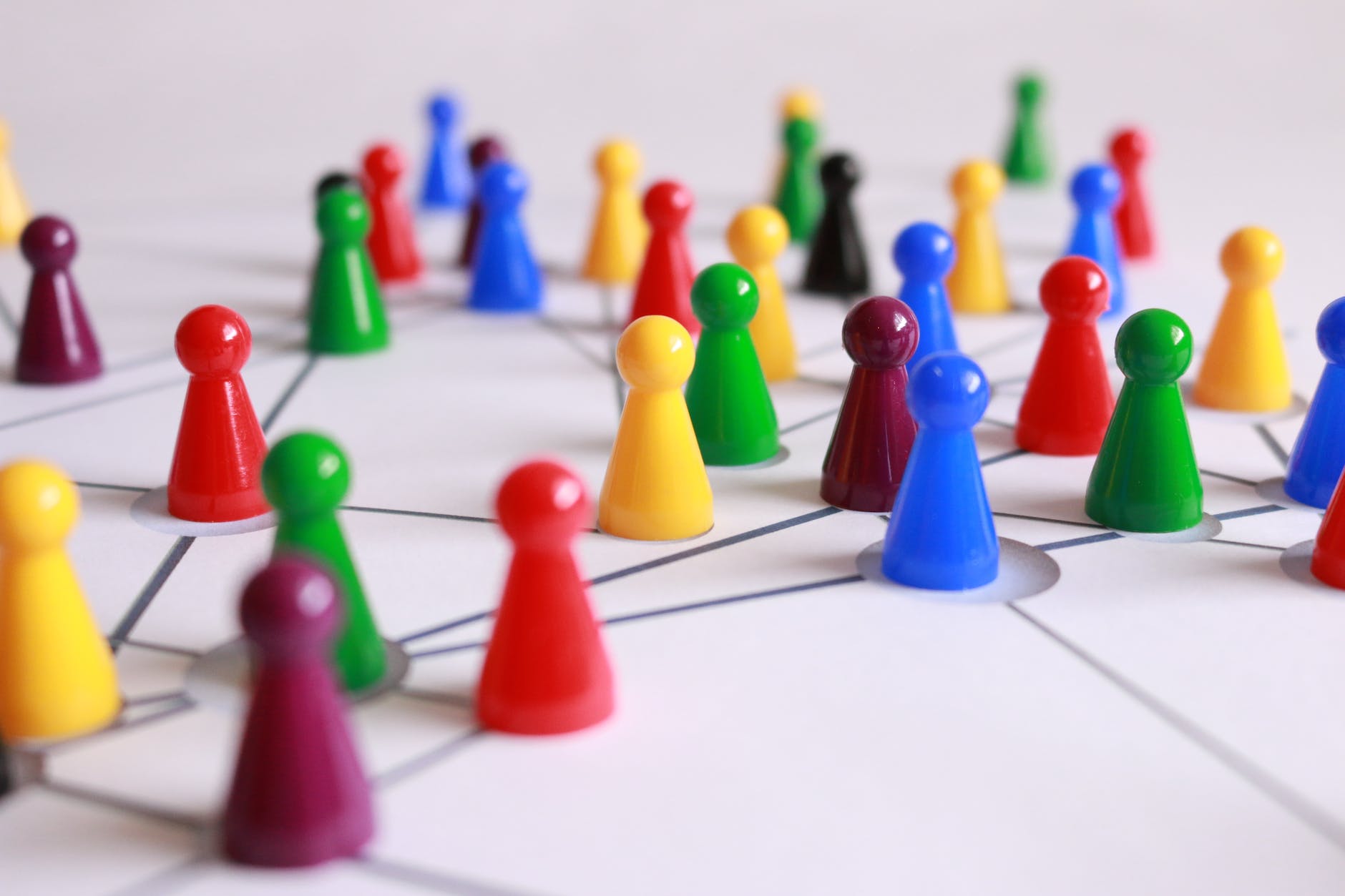 Multicoloured plastic pegs representing people on a board with lines between them. This is suggesting networks and lines of connection.