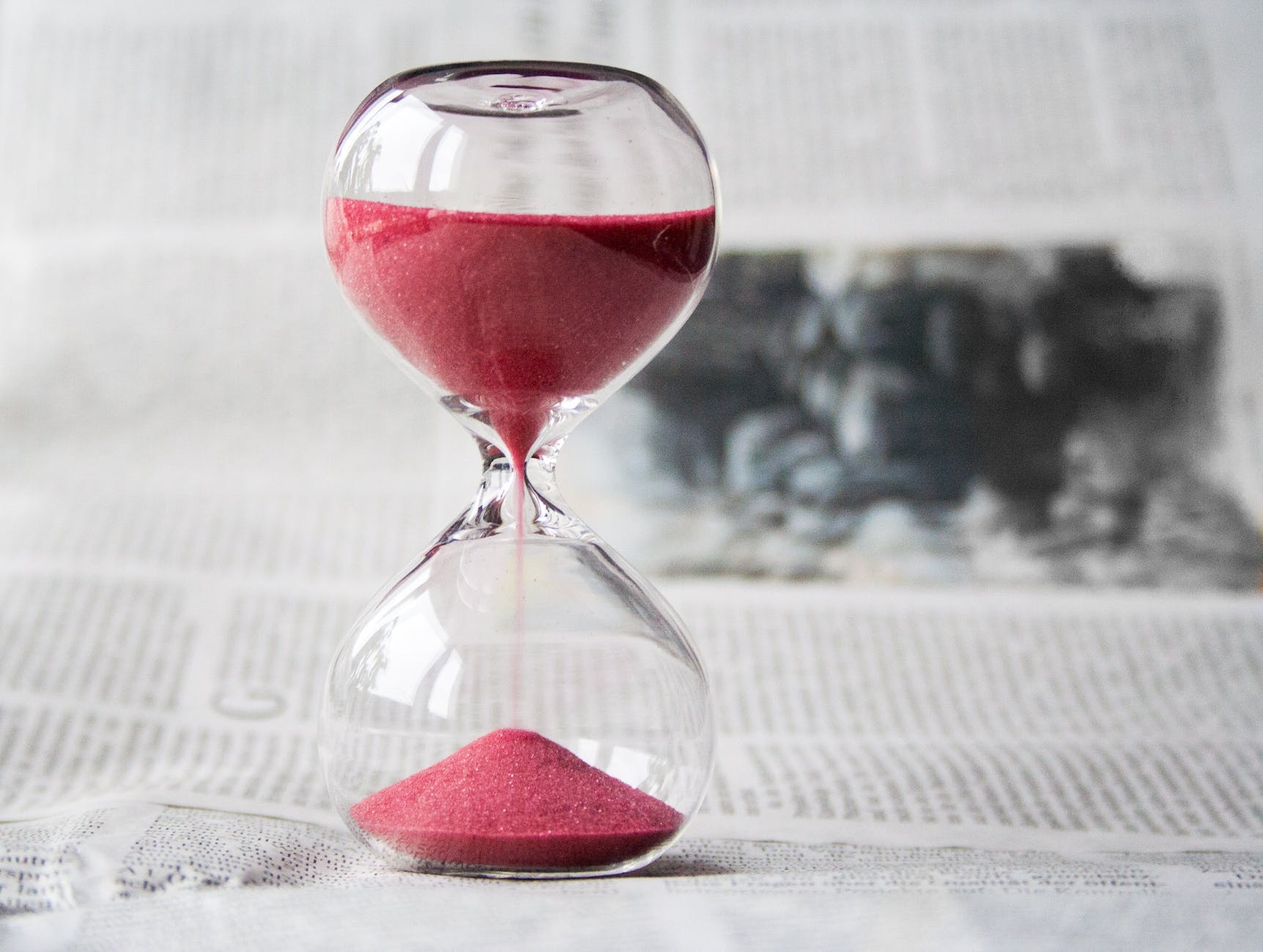 Picture of a sand timer filled with red sand, about a quarter of the way empty.
