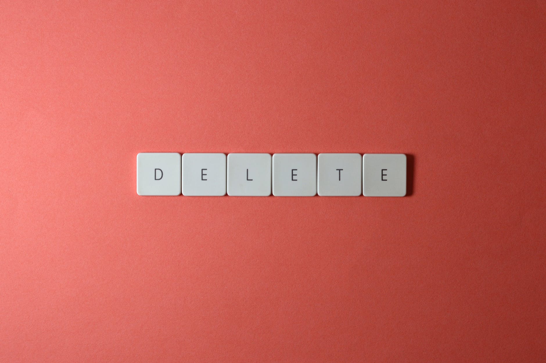 Scrabble tiles spelling 'DELETE' on a pink background