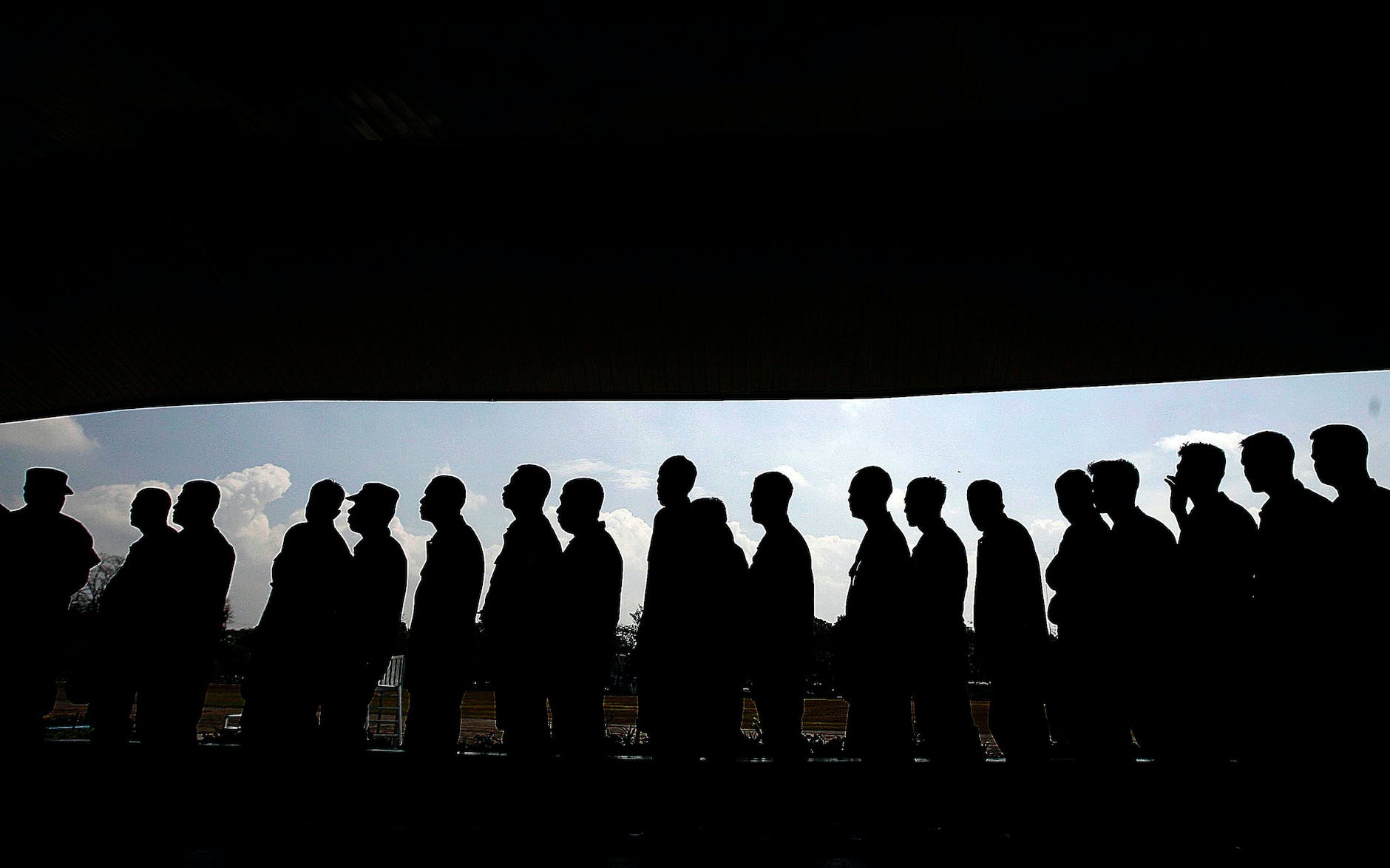 Sillouhette of men in a queue against a landscape background