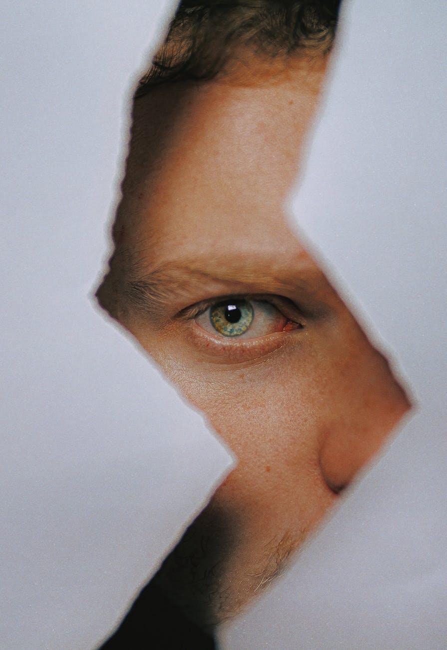 Man looking through a zig zag gap in torn paper