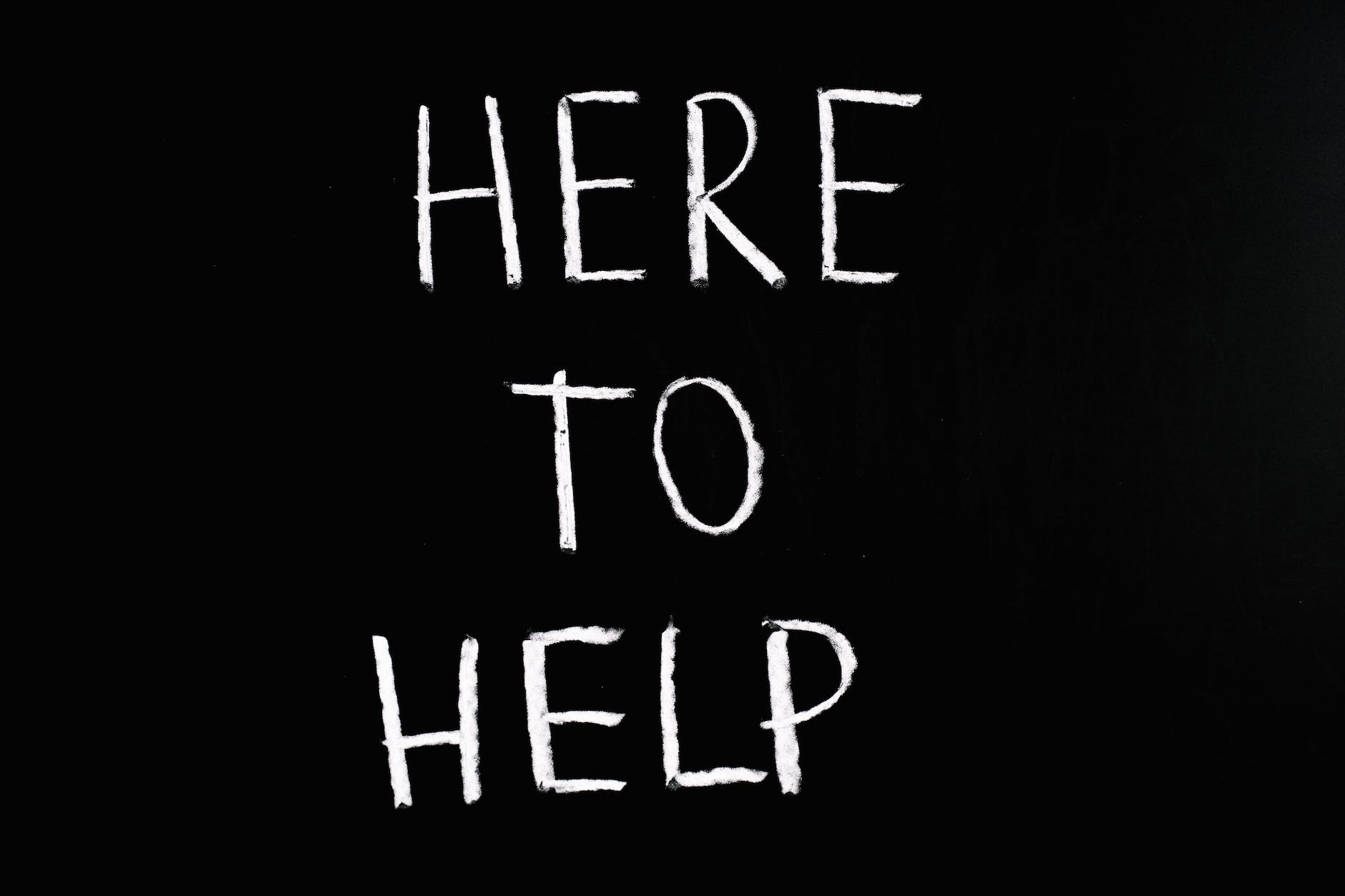 Chalkboard with 'HERE TO HELP' written in white chalk.
