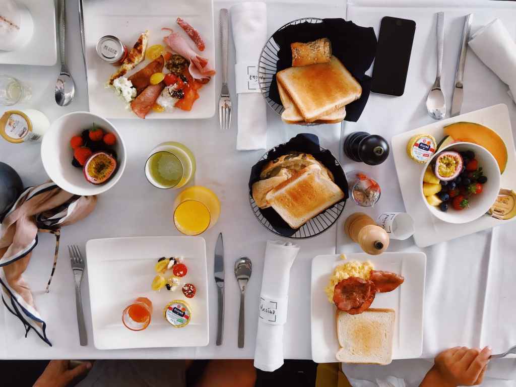 A picture of a full breakfast table with an assortment of breakfast foods, taken from above.