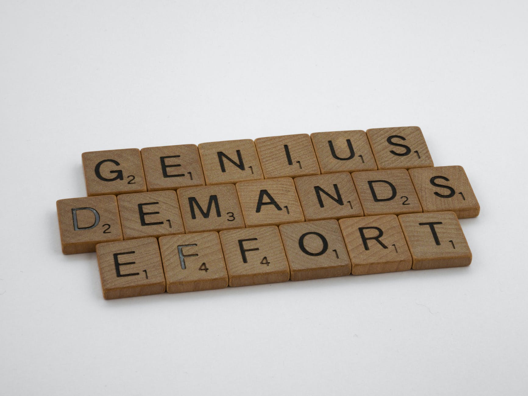 Scrabble tiles reading 'GENIUS DEMANDS EFFORT'