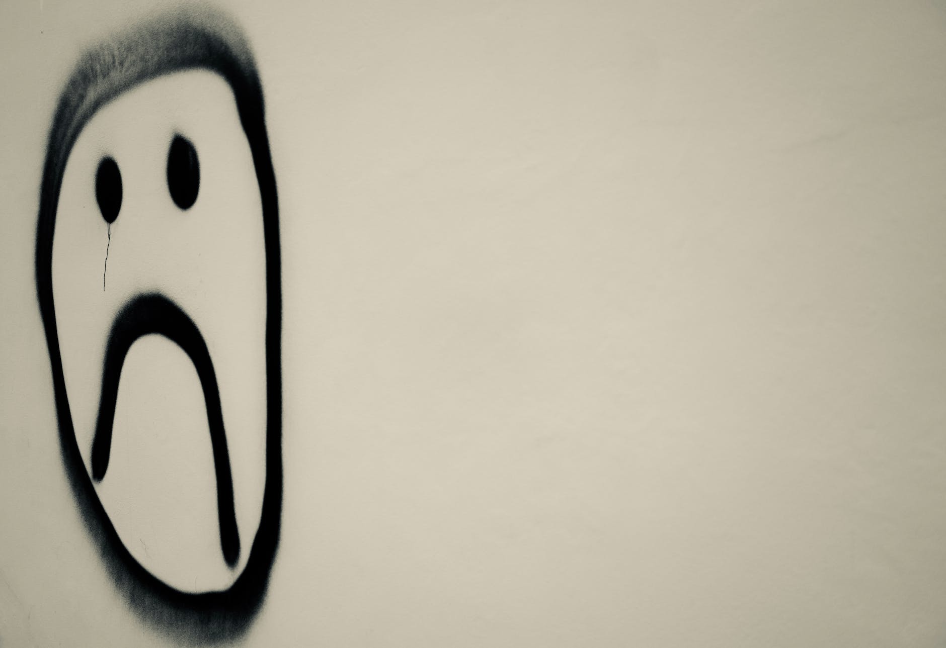 Spray painted unhappy smiley on a blank wall