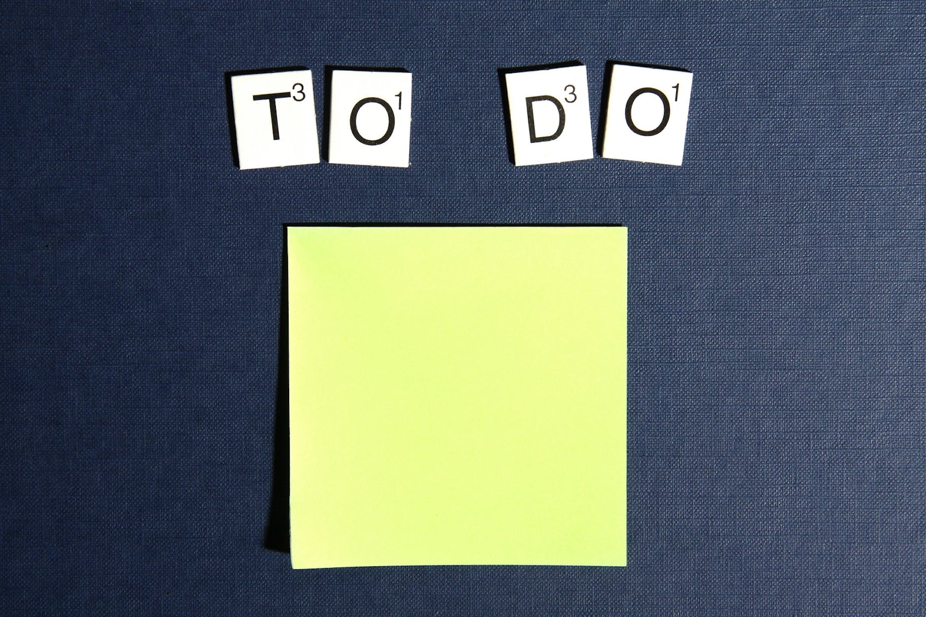 Scrabble tiles spelling 'To do' over a blank yellow post it note.