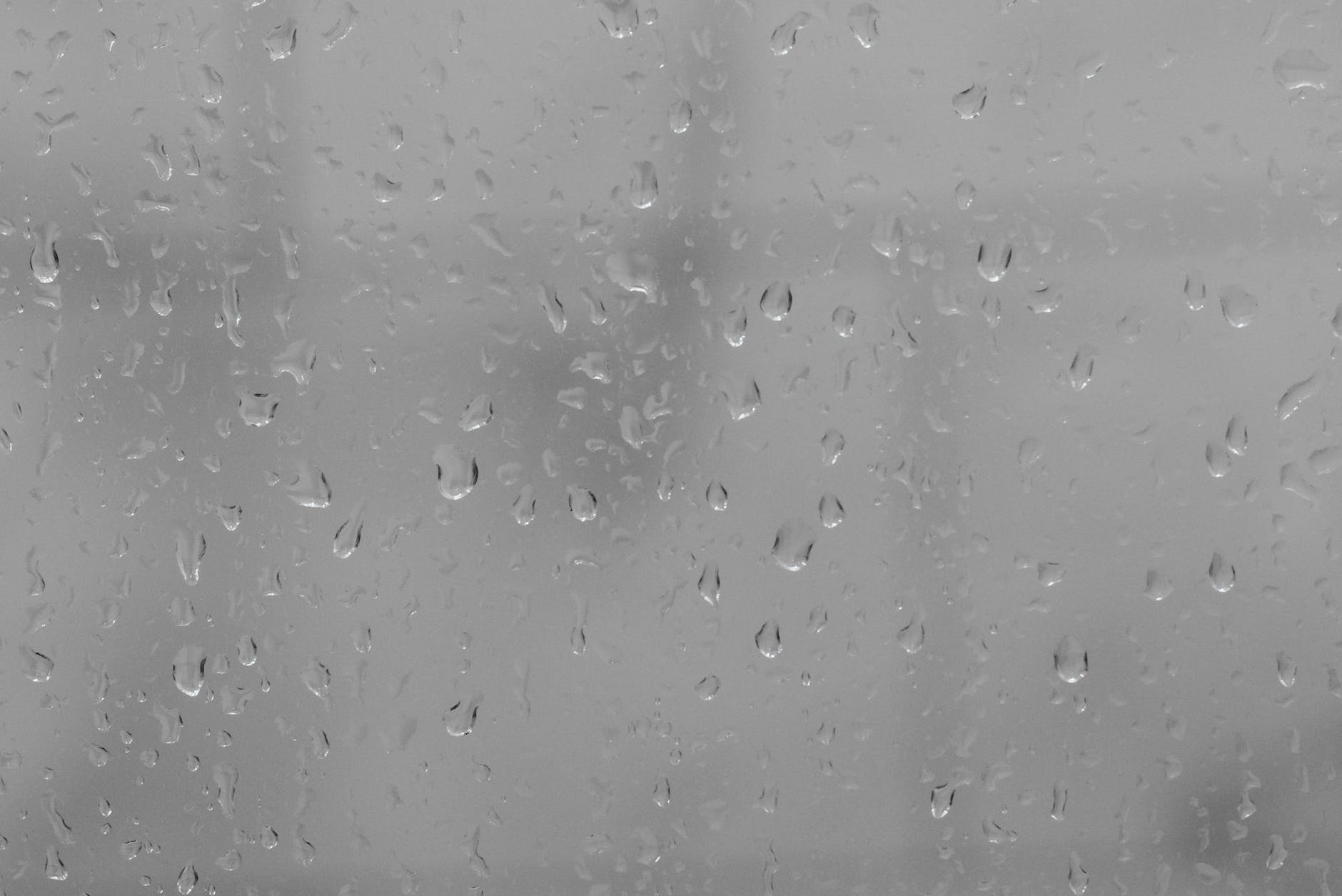 Raindrops against a window. The background is grey.