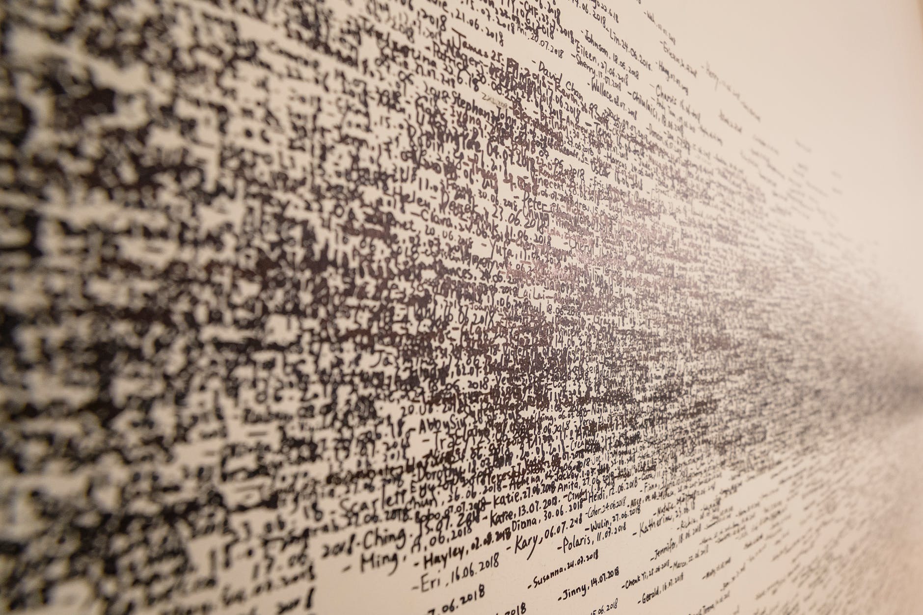 
This image shows a close-up of a textured surface covered in dense, handwritten text that blurs into streaks of ink towards the edges, creating an abstract effect.