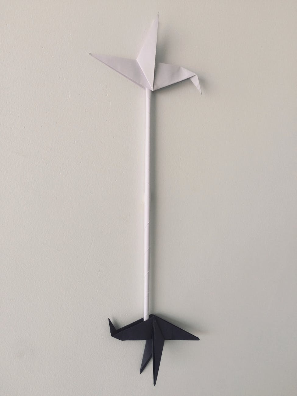 The image shows a white origami-style sculpture resembling two birds - one black and one white - positioned against a plain background.

