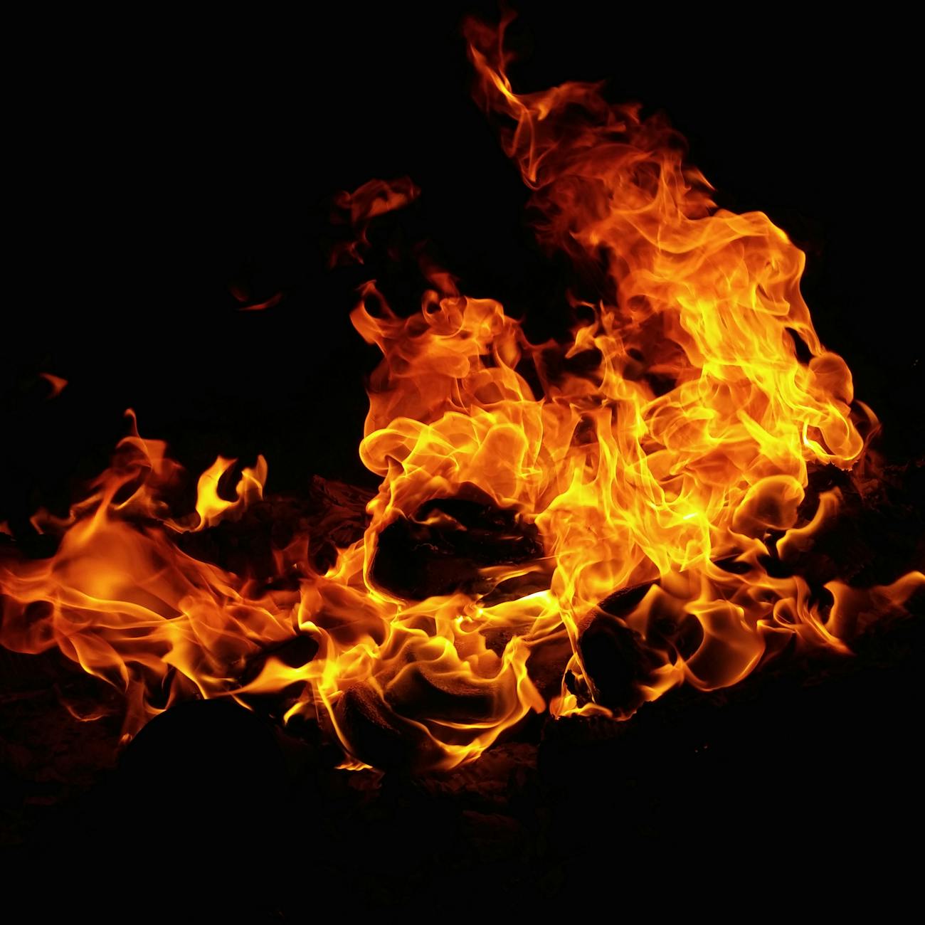 An image showing flames against a dark background. The fire is bright and intense, with the flames swirling and creating dynamic patterns of orange and yellow. 