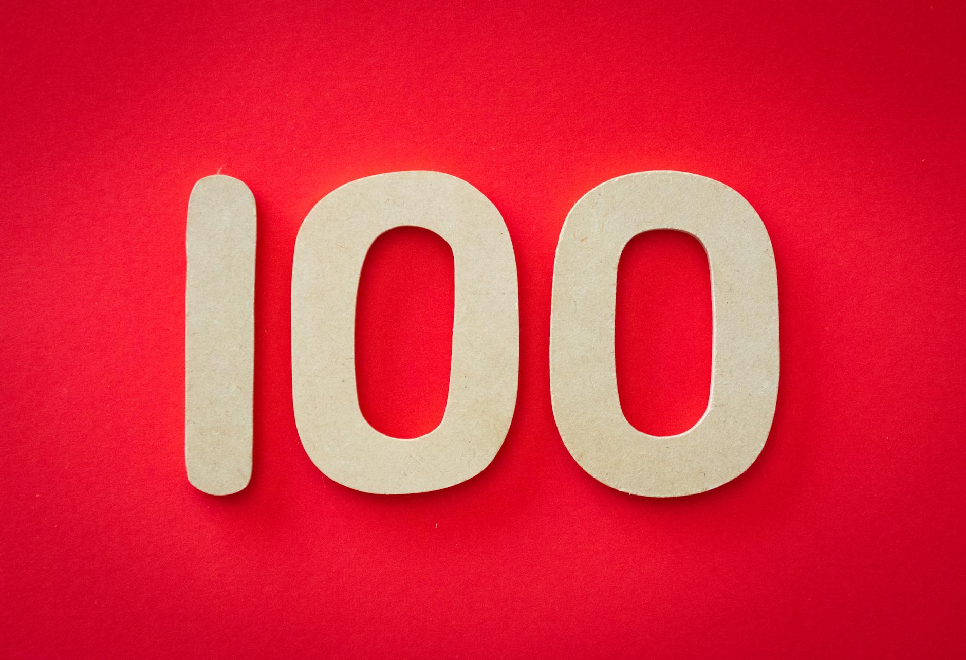 The number 100 in beige on a bright red background.