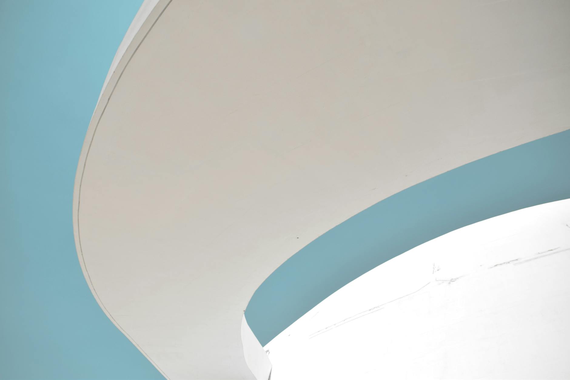 A curved white concrete panel against a blue sky.