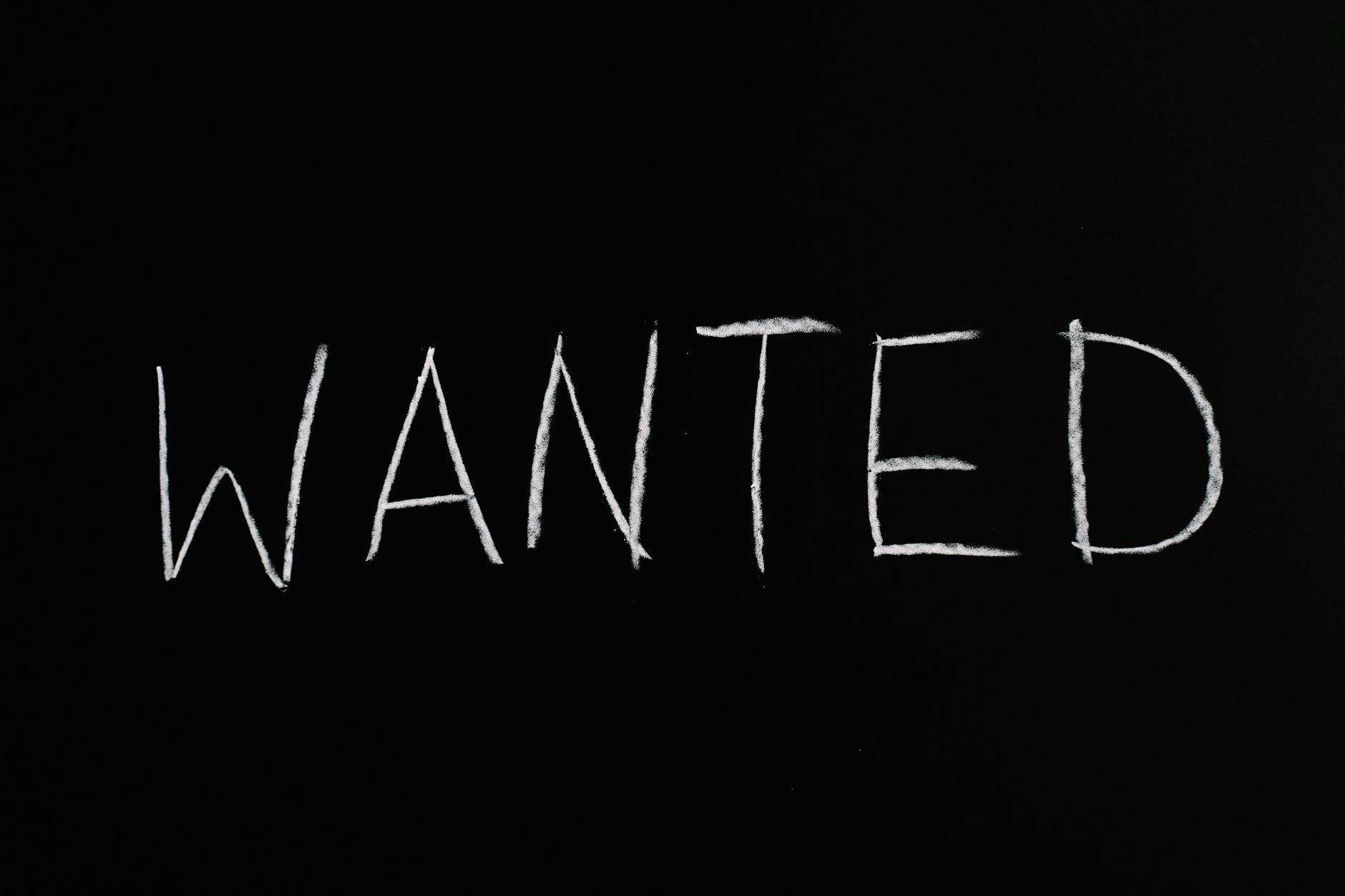 "WANTED" written in rough white chalk on a black background.