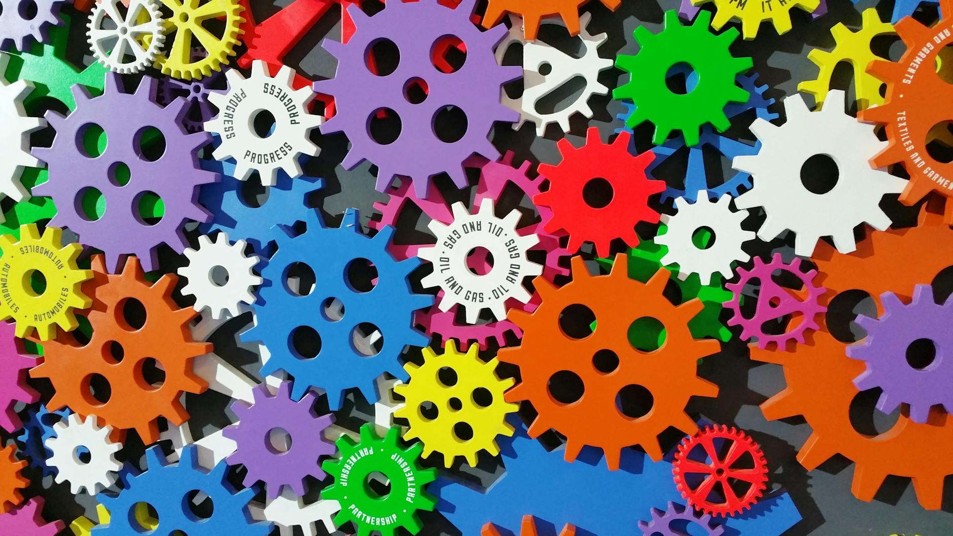A colourful array of interlocking gears in various sizes with labels like "Progress" and "Partnership."