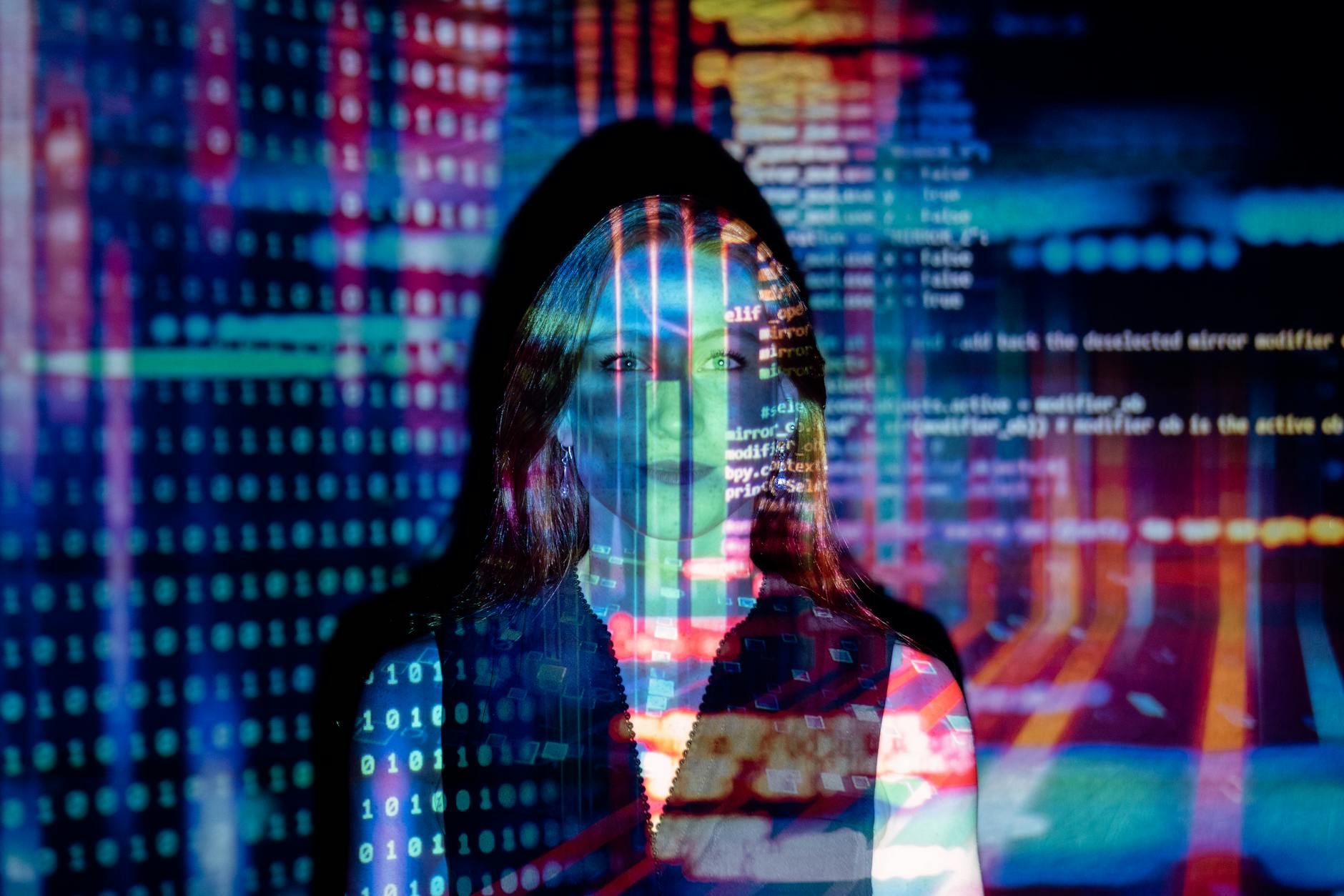 A woman stands immersed in projected code and data, blending into a futuristic digital environment.