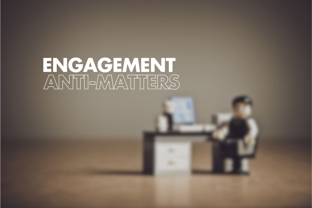 A blurred image of a desk with a computer and a seated toy figure, featuring the text "ENGAGEMENT ANTI-MATTERS" prominently on the left side.