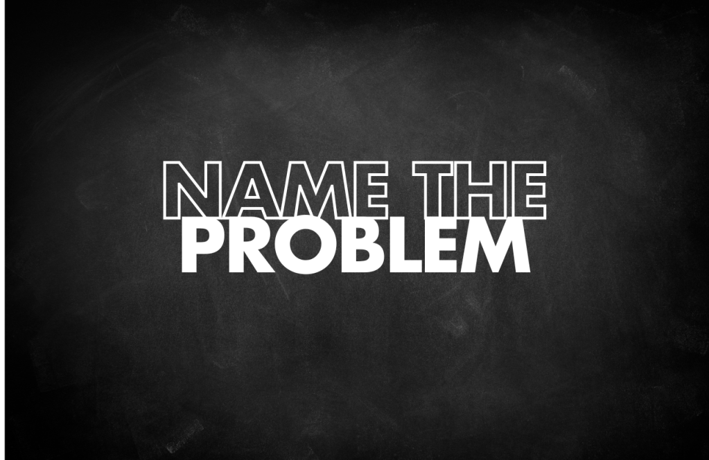 Black chalkboard with white stylised text reading 'NAME THE PROBLEM'