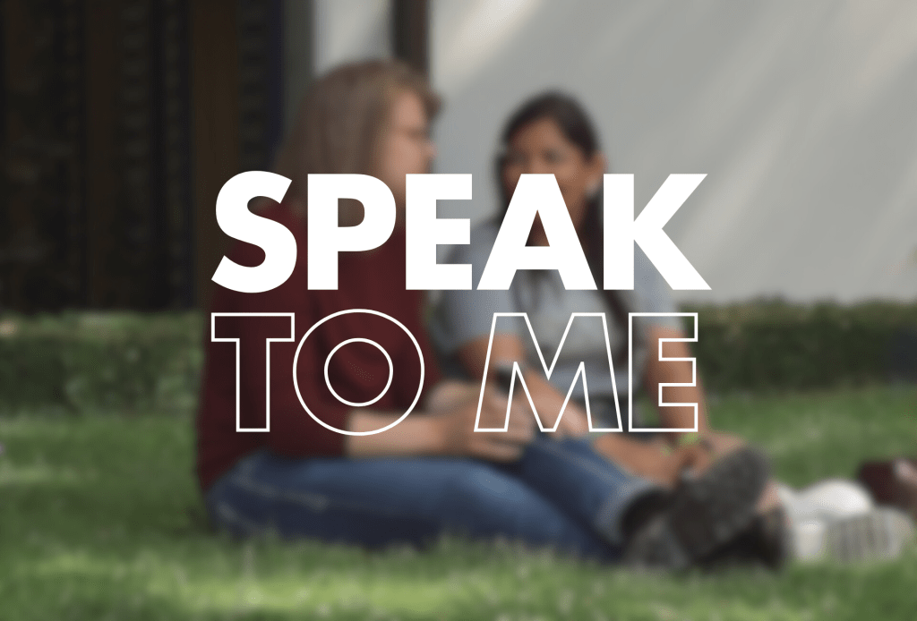 This image features the text "SPEAK TO ME" in bold white letters overlaid on a blurred background image that shows people sitting or lounging on grass