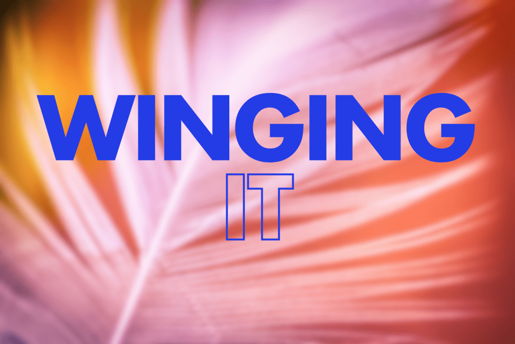 The image shows the phrase "WINGING IT" displayed in bold blue text. The words "WINGING" appear in large, solid blue capital letters at the top, while "IT" is shown below in a blue outline style. The text is set against a blurred white feather across an orange hued background.