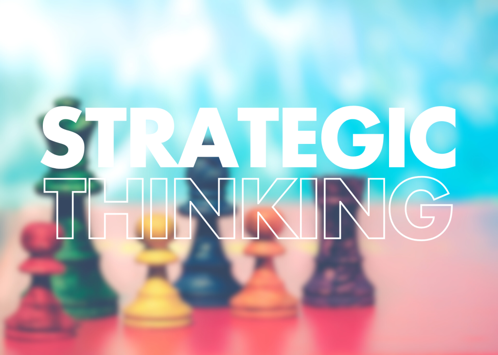 A blurred image of colourful chess pieces, with the words "STRATEGIC THINKING" prominently displayed in large, bold white text.

