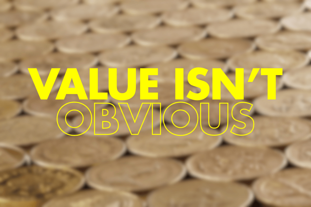 Alt Text: A blurred image of a surface covered with coins, featuring the words "VALUE ISN'T OBVIOUS" prominently displayed in large, bold yellow text.


