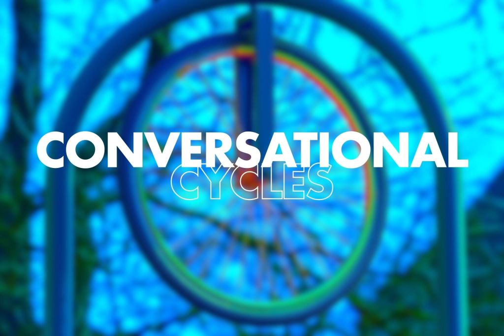 A blurred image of a colourful bicycle wheel, with the words "CONVERSATIONAL CYCLES" prominently displayed in large, bold white text.
