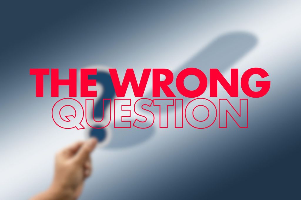 A blurred image featuring a hand holding a question mark cutout, with the words "THE WRONG QUESTION" prominently displayed in large, bold red text.