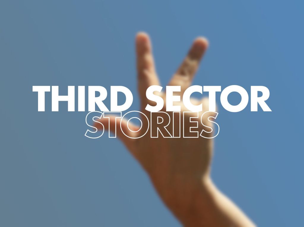  A blurred image of a hand holding up three fingers against a clear blue sky, featuring the words "THIRD SECTOR STORIES" prominently displayed in large, bold white text.