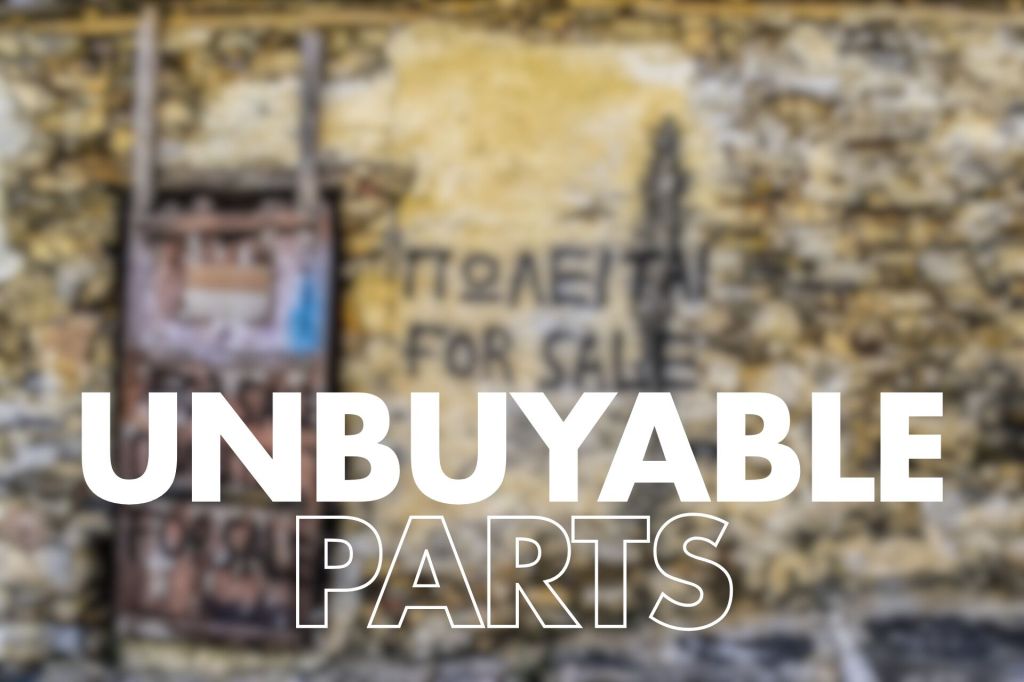 : A textured stone wall with a partially obscured sign featuring the words "FOR SALE" and Greek text. The foreground has the bold text "UNBUYABLE PARTS," which stands out prominently against the blurred background.