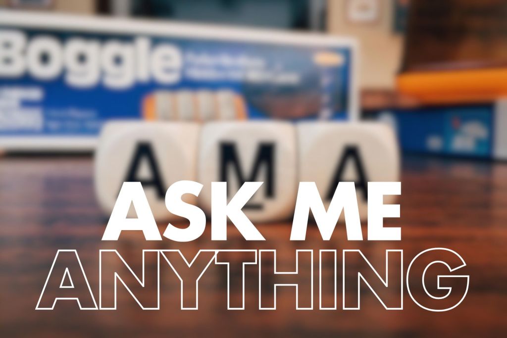 The image features a blurred background of a Boggle game box, likely for Boggle, with colourful components peeking through. In the foreground, the bold text "ASK ME ANYTHING" is prominently displayed in large, white letters. The focus is on three dice that clearly spell out "AMA," reinforcing the theme of an open Q&A session. The overall composition invites interaction and engagement.

