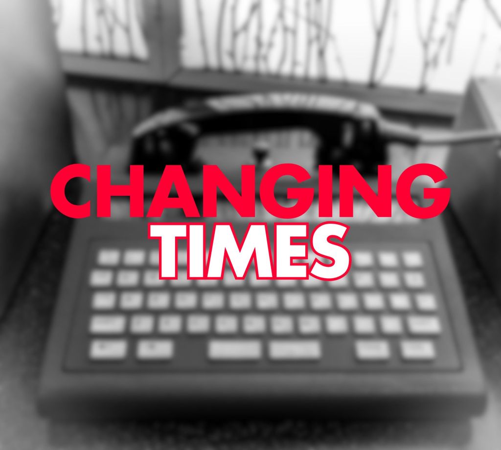 Large bold red text "CHANGING" above white filled text "TIMES" with a red outline, centred over a heavily blurred black-and-white close-up of a vintage telephone modem.