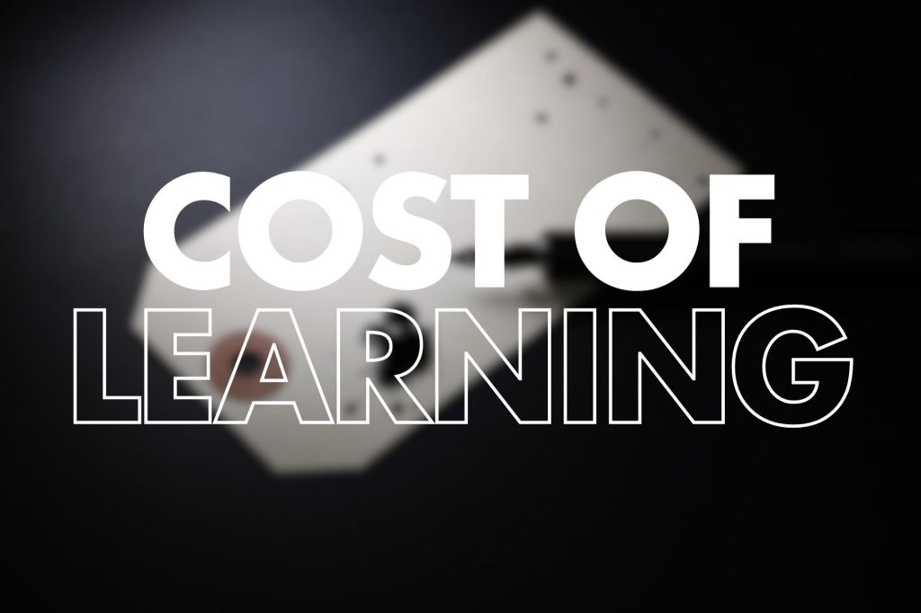 Large white text "COST OF" in bold and "LEARNING" in white outline centred over a blurred dark background showing an out-of-focus white price tag with a large ink blot from a fountain pen.