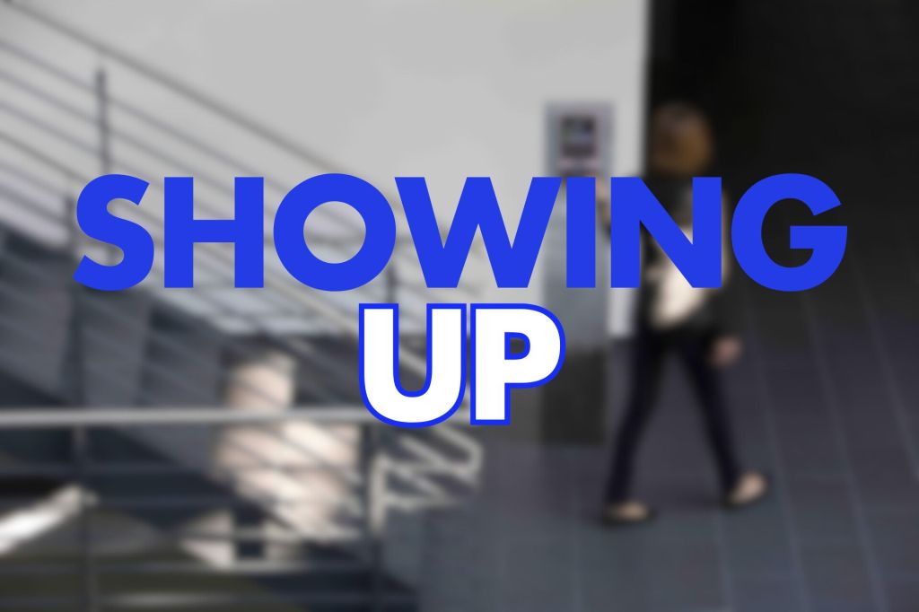 A blurred image of a person walking past a staircase, with bold text overlay that reads "SHOWING UP" in blue and white.